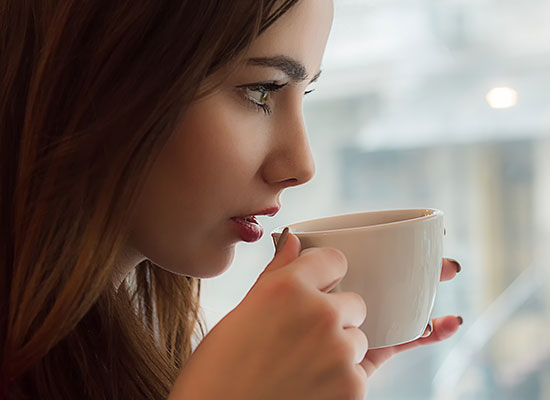 Happy employee drinking a hot latte in her office